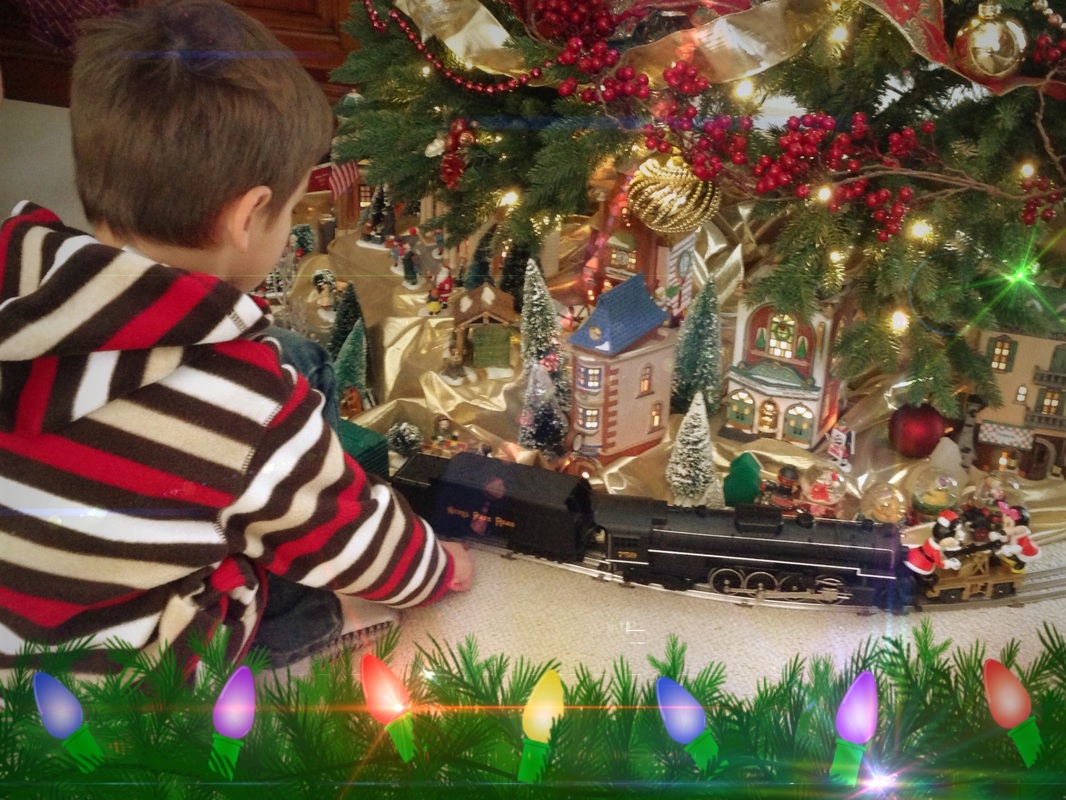Holiday Traditions Light the Season: little boy watching a toy train run under a Christmas tree