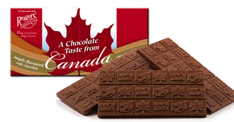 Slabs of Chocolate bars agains white candy box, with red maple leaf and red bars that say a chocolate taste from canada, maple syrup